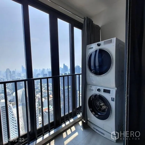 Condominium for rent in Watthana, Bangkok - Private balcony with stacked washer and dryer and expansive skyline outlook.