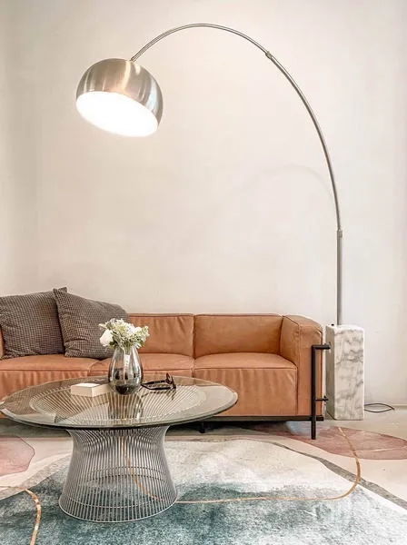 ทาวน์เฮาส์ ให้เช่าในHuai Khwang, Bangkok - มุมนั่งเล่นอบอุ่นด้วยโซฟาหนังสีน้ำตาล โคมไฟขาโค้ง และโต๊ะกระจกบนพรมลาย