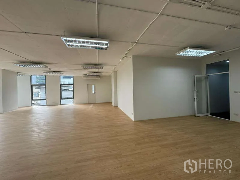 Office Space for rent in Sathon, Bangkok - Open-plan office with wood flooring, white walls, fluorescent lighting, glass-door room and city-facing windows.