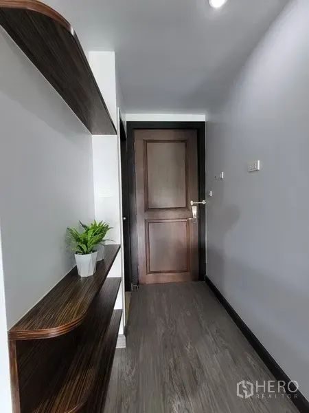 Condominium for rent in Phra Khanong, Bangkok - Bright entry corridor with floating wooden shelves and a solid wood door.