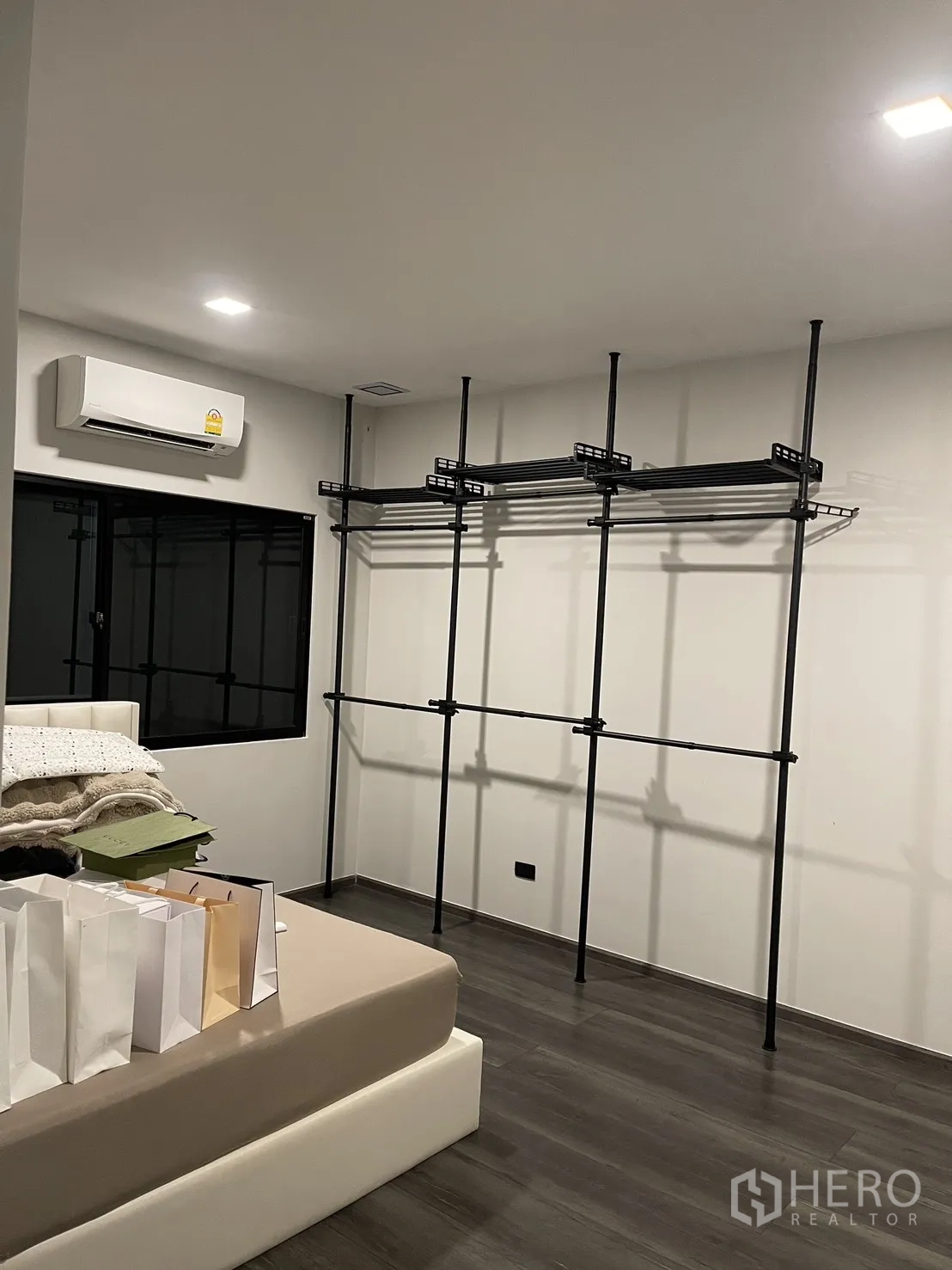Townhouse for sale in Bang Phli, Samut Prakan - Bedroom with open metal wardrobe system, wood floors, and air conditioner.