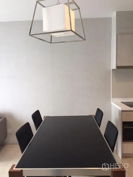 คอนโด ให้เช่าในKhlong Toei, Bangkok - มุมรับประทานอาหาร โต๊ะท็อปสีดำ เก้าอี้สี่ตัว และโคมไฟทรงลูกบาศก์สไตล์โมเดิร์น