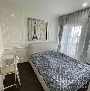 Condominium for rent or sale - Cozy bedroom with upholstered bed, Eiffel Tower artwork, desk, and floor-to-ceiling window with sheer drapes.