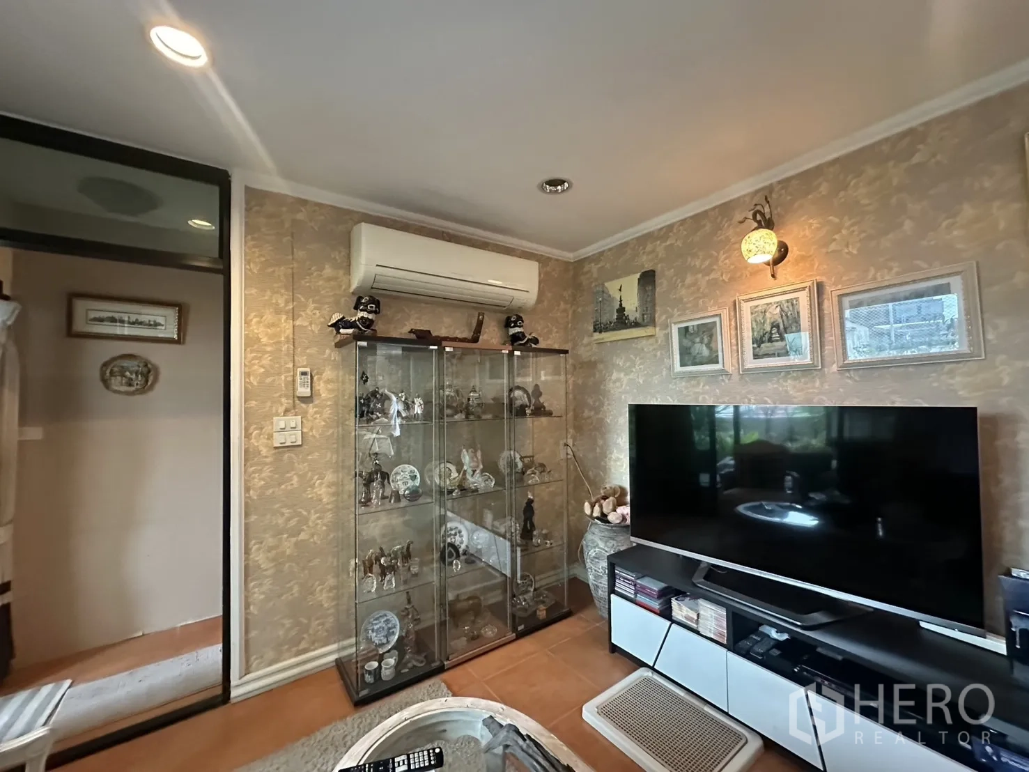 Shophouse for sale in Watthana, Bangkok - TV lounge with glass display cabinet, large flat-screen and wall art.