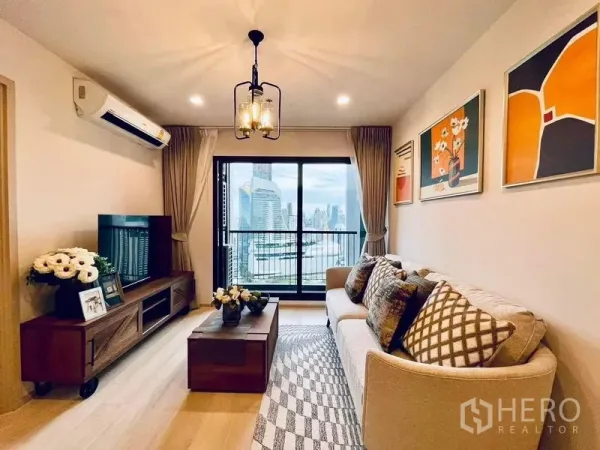Condominium for rent in Pathum Wan, Bangkok - Cozy living room with cream sofa, wood TV console, pendant light and balcony showcasing Bangkok skyline.