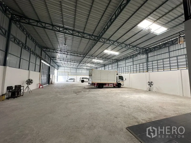 คลังสินค้า ให้เช่าในLam Luk Ka, Pathum Thani - พื้นโกดังโล่งมีรถบรรทุกจอด ใต้ช่องแสงสกายไลท์และผนังระบายอากาศ