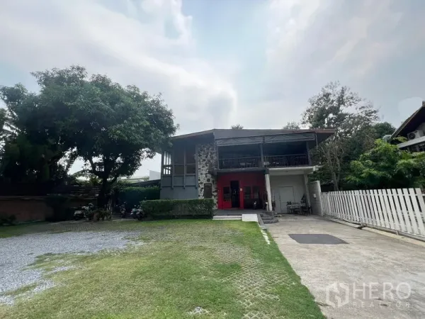 บ้าน ให้เช่าในKhlong Toei, Bangkok - บ้านเดี่ยวสองชั้น ผนังหิน ประตูสีแดง สนามหญ้าและทางรถเข้า ใกล้ BTS เอกมัย