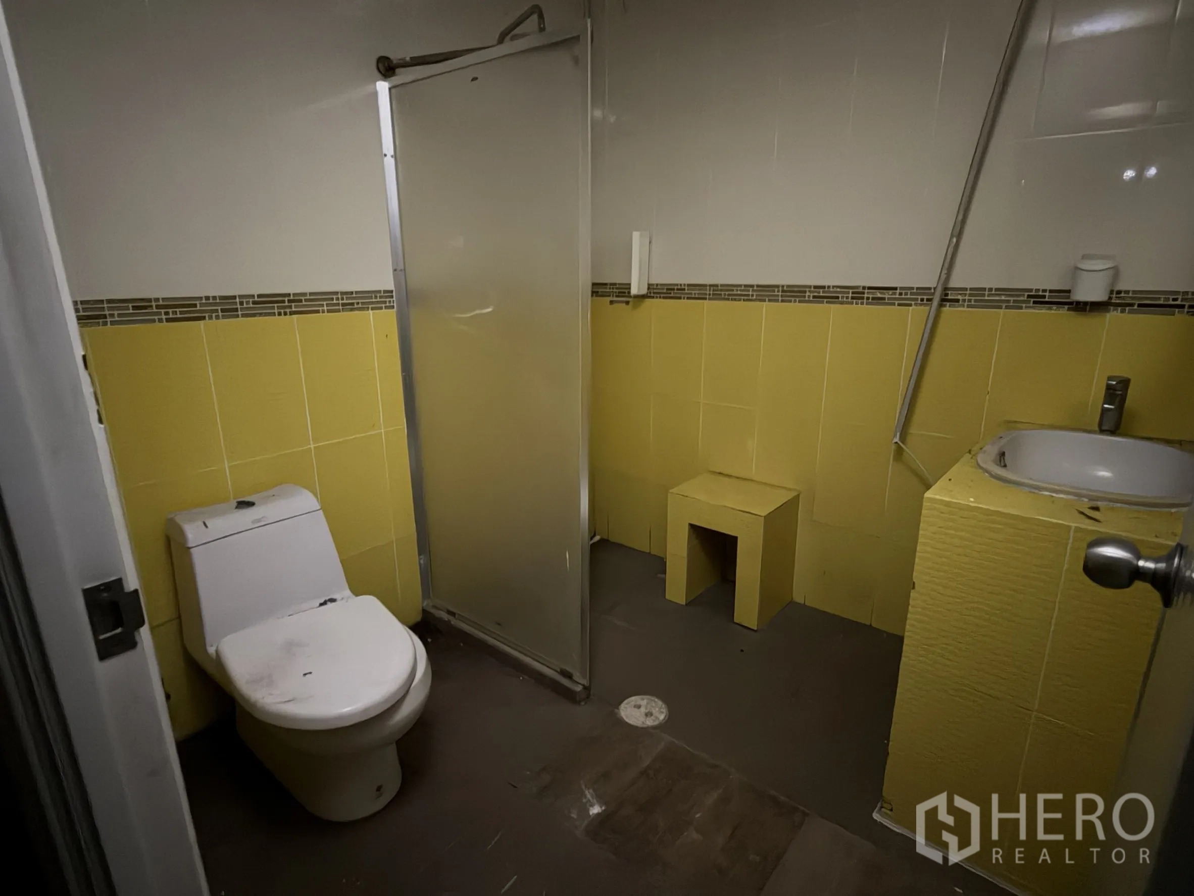 Shophouse for rent in Sathon, Bangkok - Bathroom with yellow wall tiles, toilet, sink and a shower screen.
