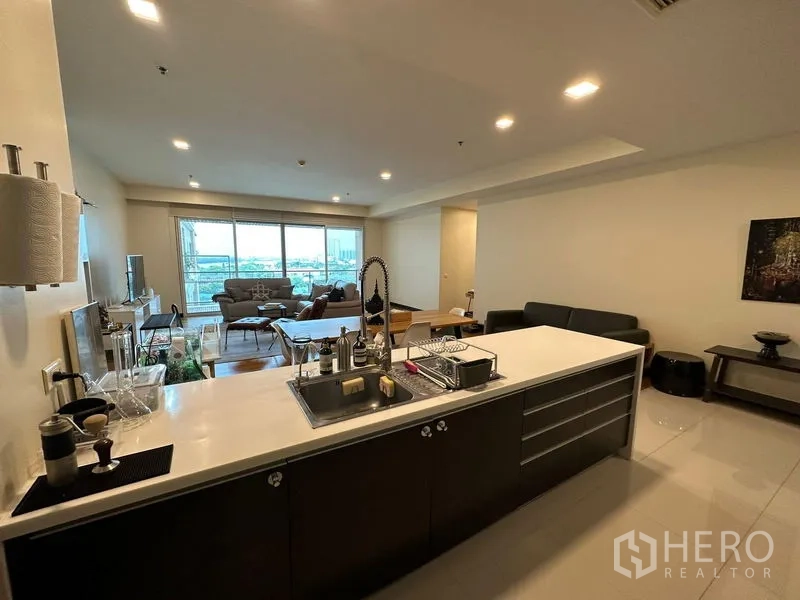 Condominium for rent in Yan Nawa, Bangkok - Kitchen island with sink facing the living room and balcony beyond.