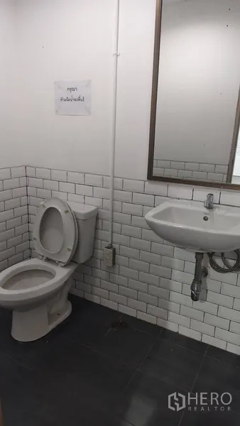 办公空间 出租在Pathum Wan, Bangkok - 卫生间，白色地铁砖墙，坐便器、洗手盆与镜子。