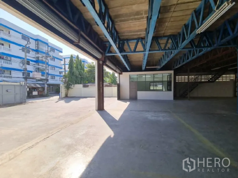 Warehouse for rent in Khlong Toei, Bangkok - Loading bay with open roller doors, blue beams and a glass-walled office.