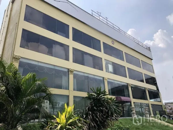 带办公室的家 出租或出售在Huai Khwang, Bangkok - 多层住宅办公楼外立面，整面玻璃窗与前方绿植，位于曼谷 Huai Khwang 区