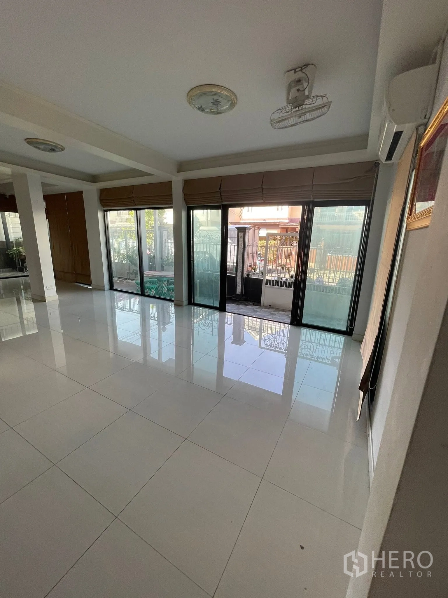 Detached House for rent or sale in Lam Luk Ka, Pathum Thani - Front living space with multiple sliding glass doors and an air conditioner.