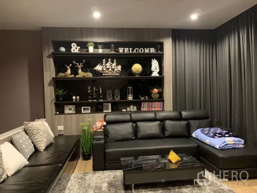 ทาวน์เฮาส์ ให้เช่าในSuan Luang, Bangkok - ห้องนั่งเล่นสไตล์โมเดิร์น โซฟาหนังสีดำ ชั้นวางบิวท์อิน และผ้าม่านทึบ