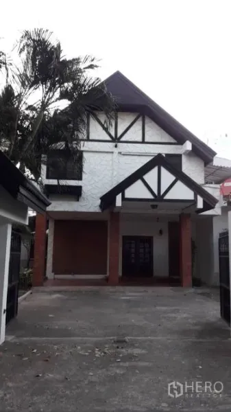 บ้าน ให้เช่าในYan Nawa, Bangkok - ด้านหน้าบ้านสองชั้นหลังคาจั่ว แต่งคานสีดำ มีทางจอดรถและกันสาด ใกล้ต้นปาล์ม