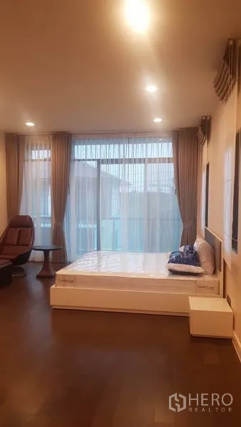 独立式住宅 出租在Saphan Sung, Bangkok - 宽敞主卧，落地窗、床与休闲椅。