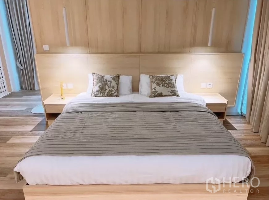 Detached House for rent in Saphan Sung, Bangkok - King‑size bed with wooden headboard, bedside tables and warm concealed lighting.
