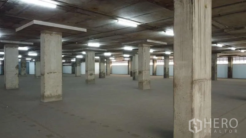 Warehouse for rent in Khlong Toei, Bangkok - Warehouse interior showing columns and closed bay doors along the side wall.