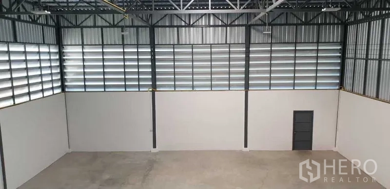 Factory for rent in Lam Luk Ka, Pathum Thani - Wide warehouse wall with horizontal louver windows and steel framing.