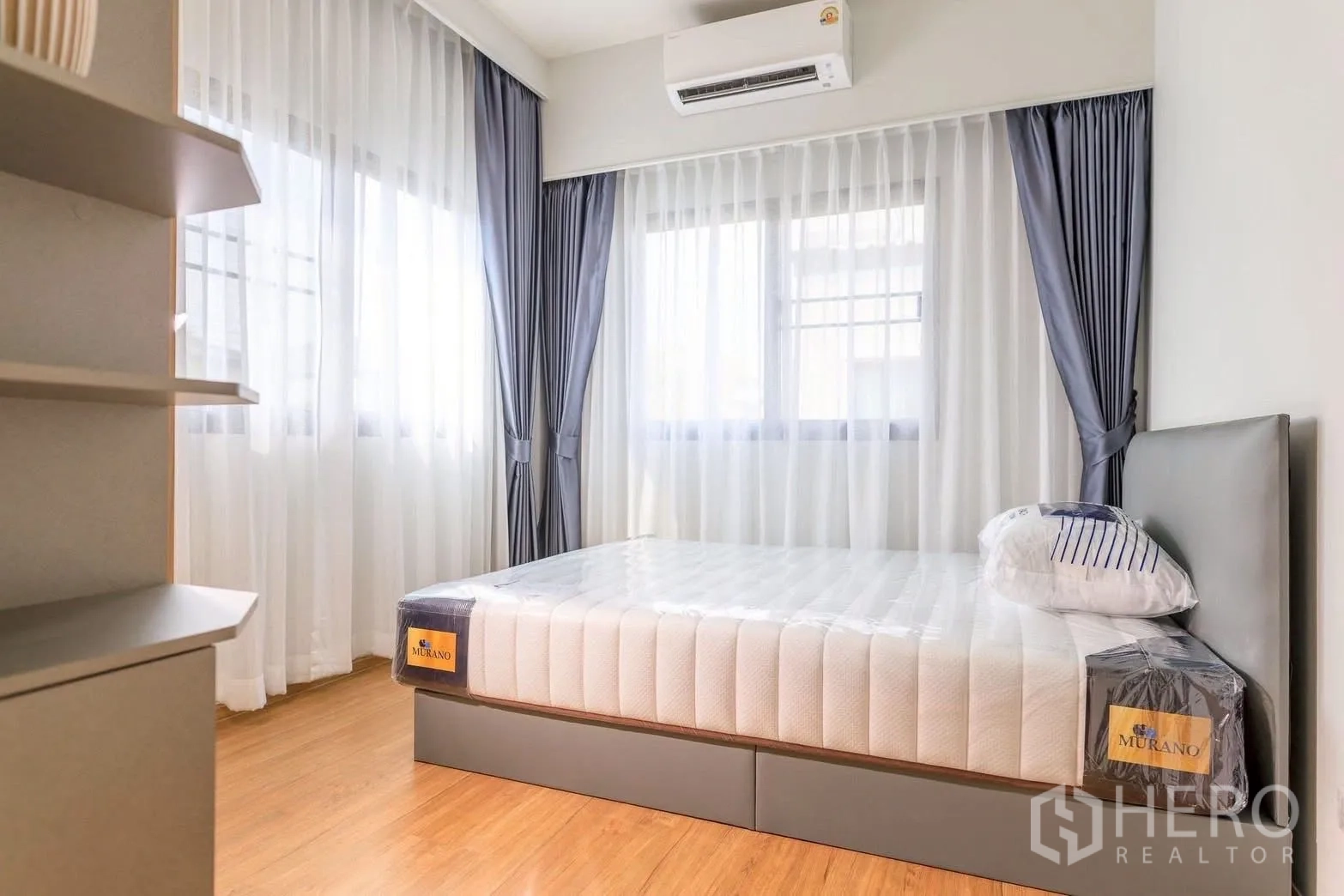 Townhouse for rent or sale in Bang Phli, Samut Prakan - Guest bedroom with air conditioner, wraparound windows and upholstered bed base.