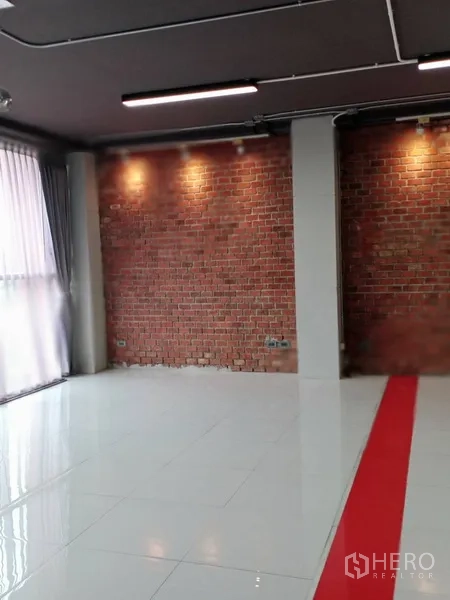 办公空间 出租在Khlong Toei, Bangkok - 红砖墙配暖色射灯，亮白地面上有红色装饰条。