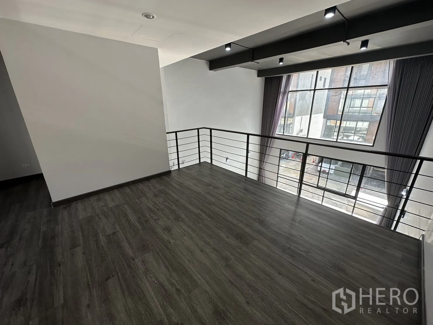 带办公室的家 出租或出售在Suan Luang, Bangkok - 自夹层俯瞰街景的大窗视野，配灰色窗帘。