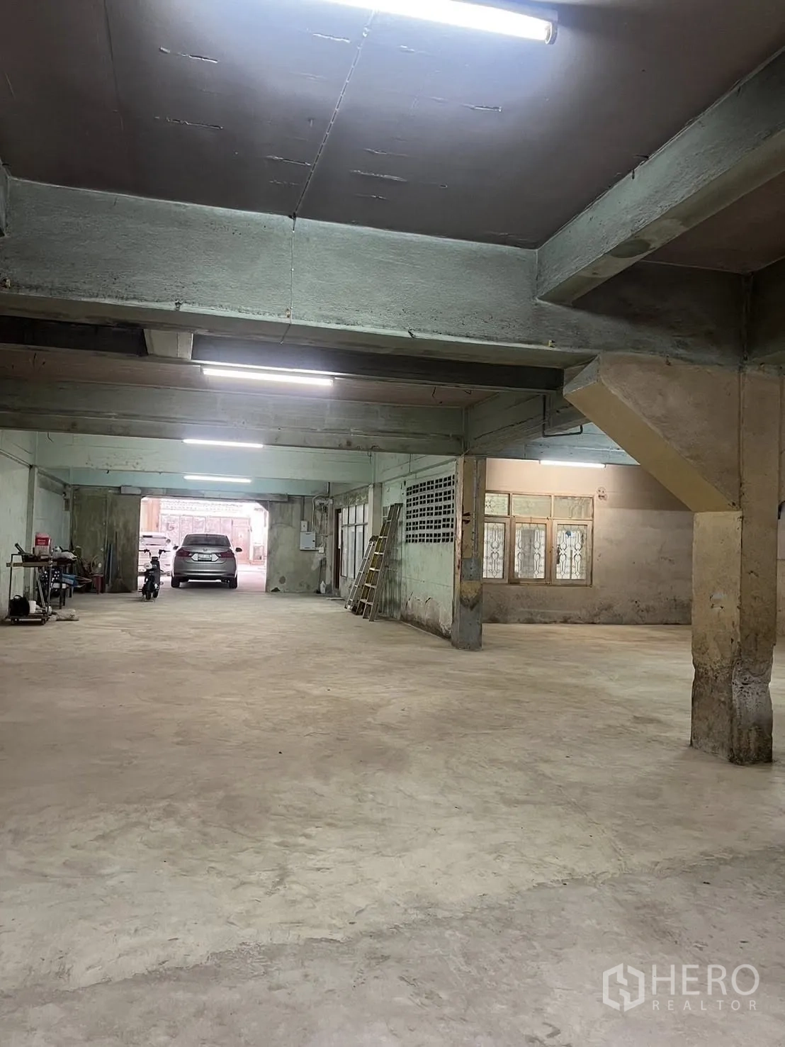 Warehouse for rent in Phra Pradaeng, Samut Prakan - Deep storage zone with beams and lighting, showing vehicle access at the far end.