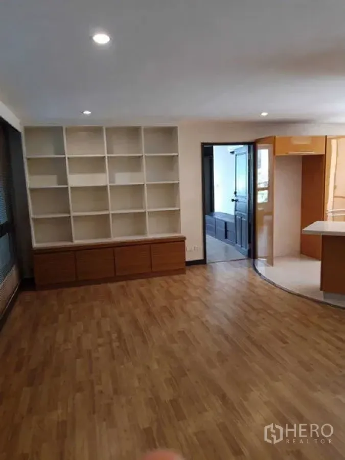 Condominium for sale - Spacious living area with built-in white shelving and wood floors.