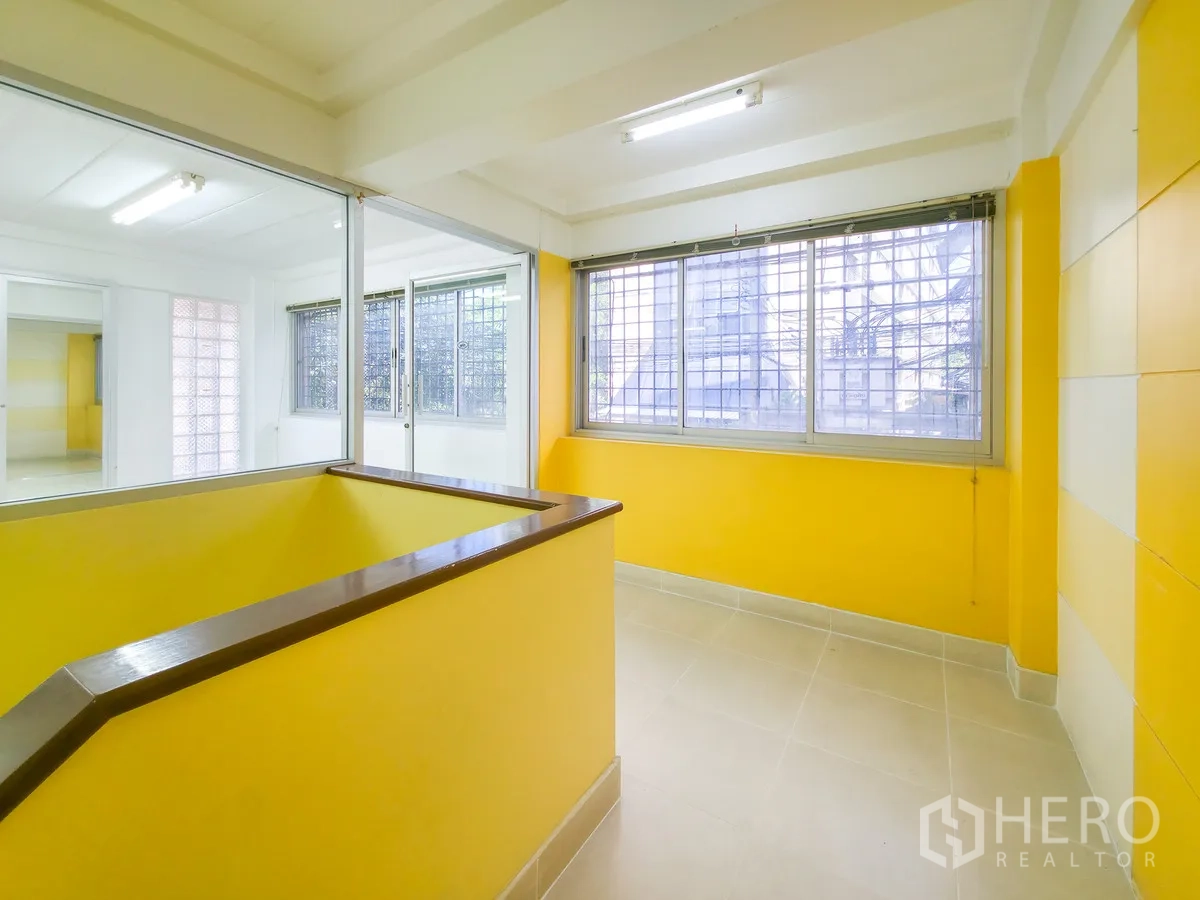 办公室 for rent in Khlong Toei, Bangkok - 黄色角落平台，大窗配防护格栅与玻璃隔断。
