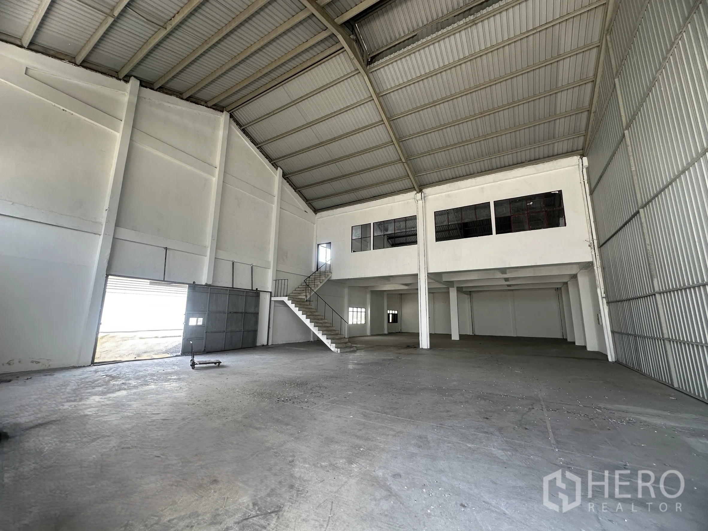 Factory for rent in Mueang Samut Prakan, Samut Prakan - Large open industrial space with ventilation louvers and sliding steel doors.