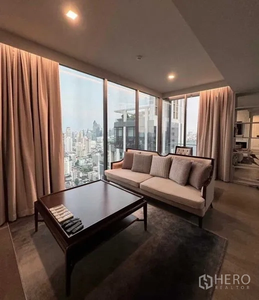 Condominium for rent in Watthana, Bangkok - Living room view showing sofa and coffee table set against expansive skyline windows.