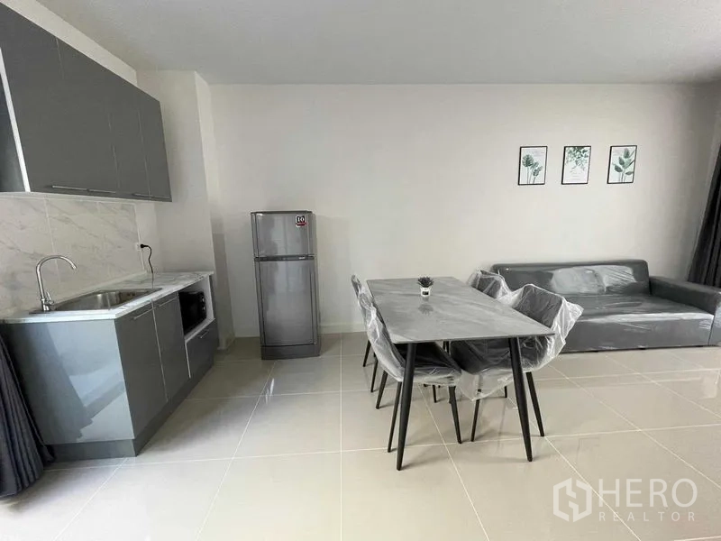 联排别墅 出租在Prawet, Bangkok - 宽敞开放式客餐厅，带简易厨房、餐桌与沙发。