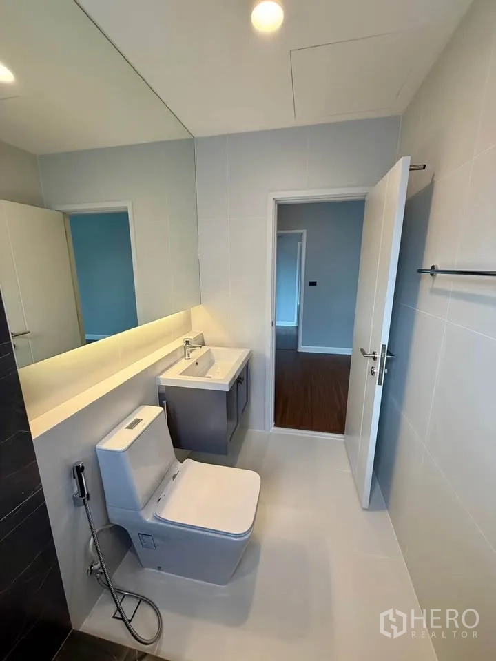 Detached House for rent in Don Mueang, Bangkok - Bright bathroom with large mirror, vanity sink, and toilet.