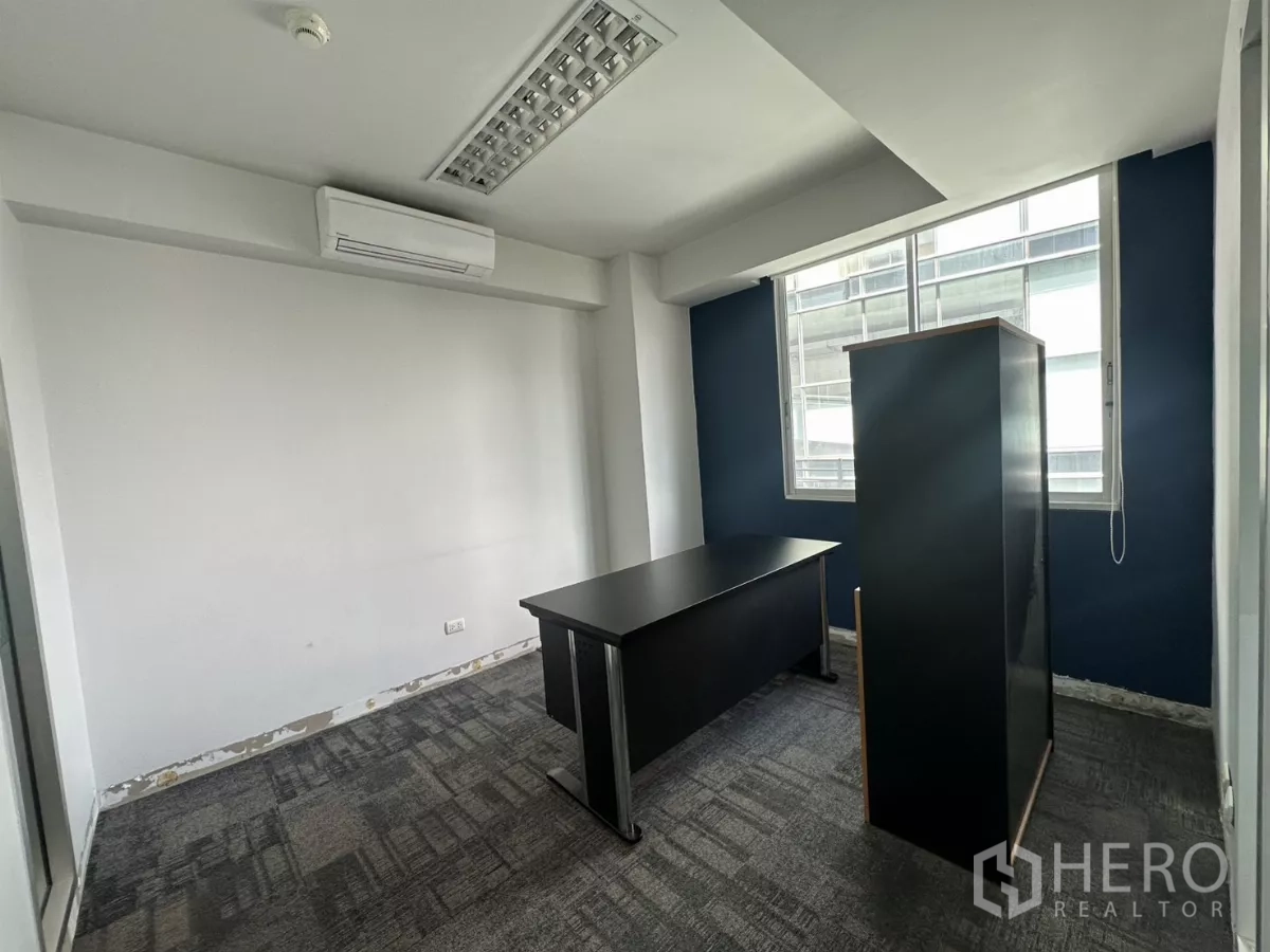 Office Space for rent in Watthana, Bangkok - Private office room with window, air-conditioning and a dark desk, showing light renovation details.