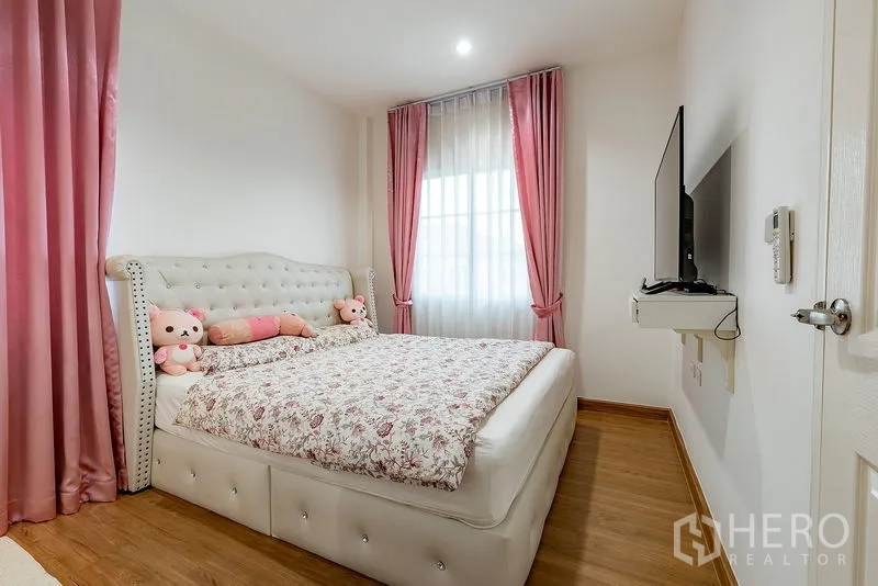 บ้าน ให้เช่าหรือขายในBang Khen, Bangkok - ห้องนอนอบอุ่น เตียงบุนุ่ม ผ้าม่านสีชมพู ชุดเครื่องนอนลายดอก และทีวีติดผนัง