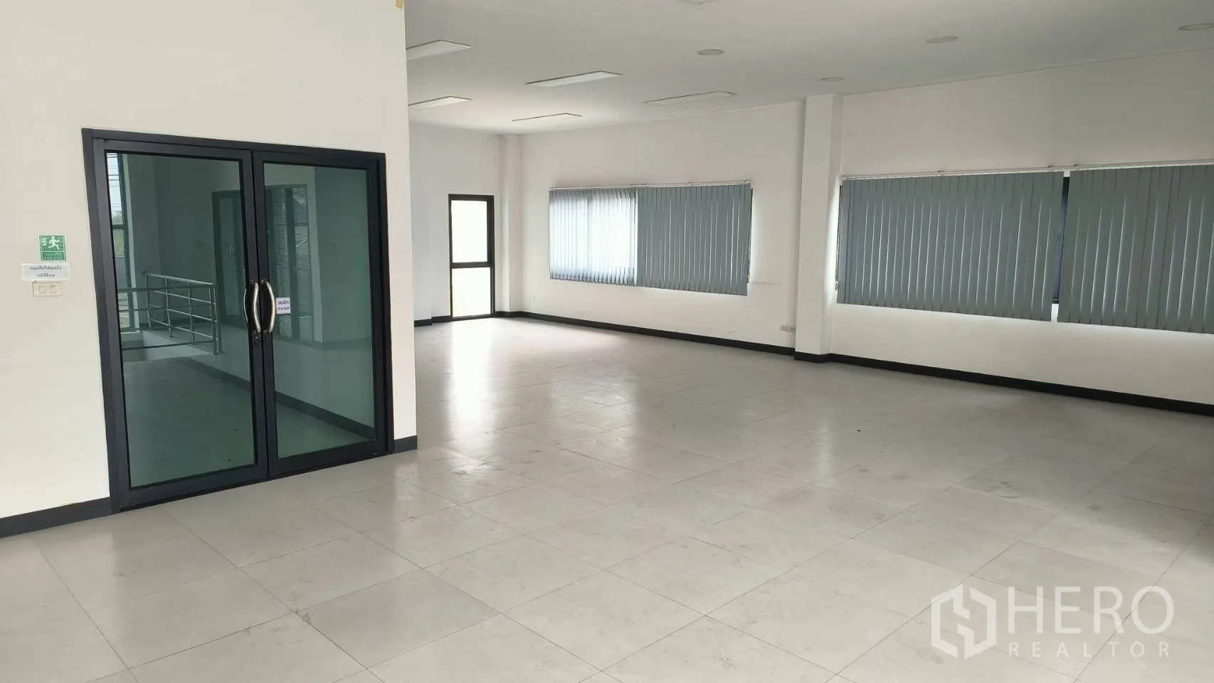 Office Space for rent in Khlong Toei, Bangkok - Bright upper-floor office with blinds and a glass door to the stair landing.