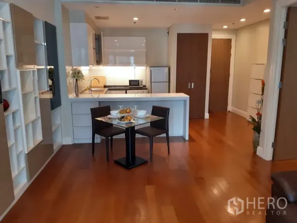 คอนโด ให้เช่าในKhlong Toei, Bangkok - พื้นที่รับประทานอาหารและครัวสีขาวแบบโอเพ่น พร้อมเคาน์เตอร์คาบิเน็ตและโต๊ะทานข้าวสำหรับสอง