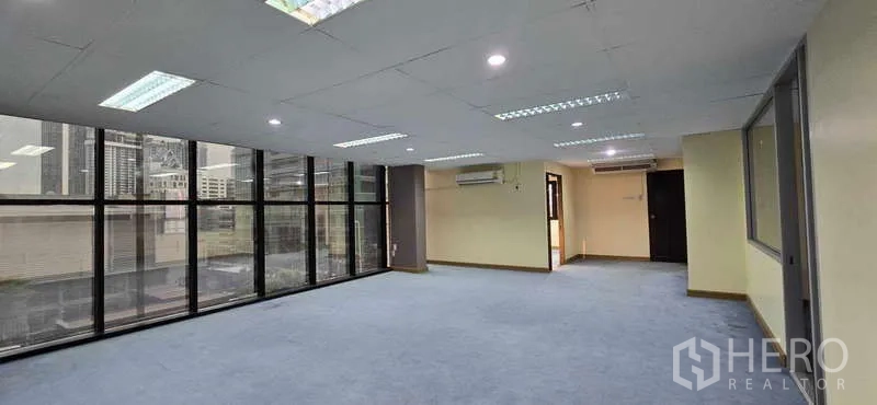 办公空间 出租 - 开放式办公室，落地窗、蓝色地毯与城市景观，曼谷CBD。