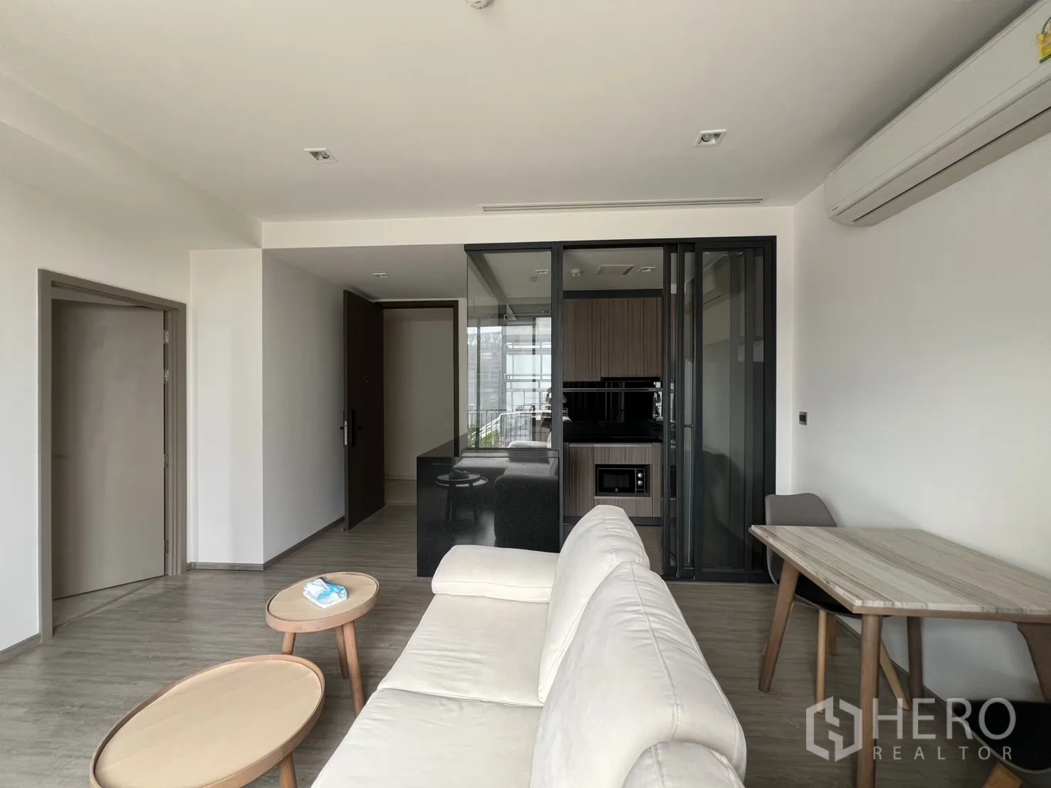 公寓 for rent in Watthana, Bangkok - 客厅内有沙发、套几、餐桌，厨房在玻璃推拉门后。