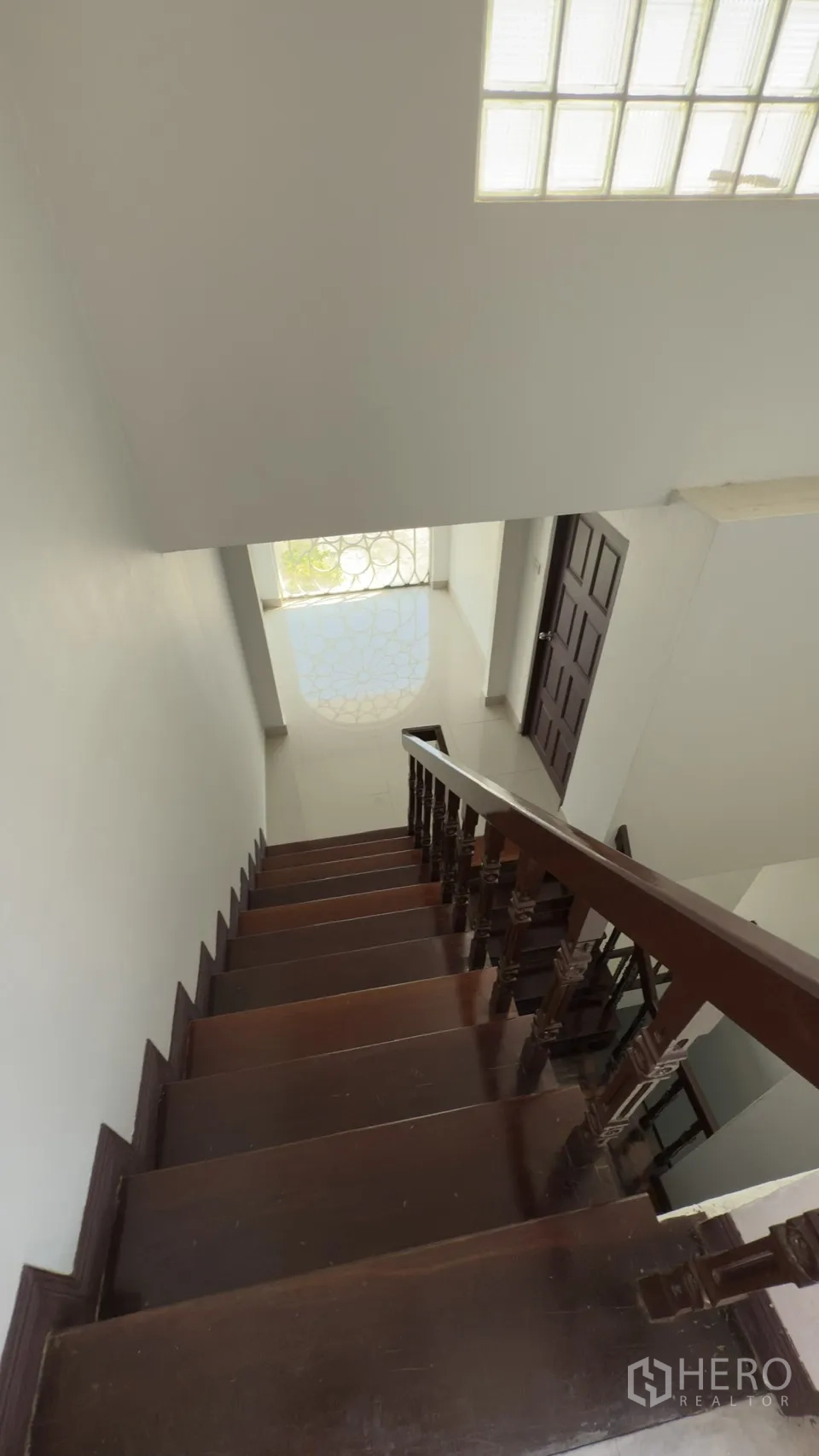 ทาวน์เฮาส์ for rent in Watthana, Bangkok - บันไดไม้ลงสู่โถงทางเข้าที่มีหน้าต่างลายฉลุรูปดอกไม้