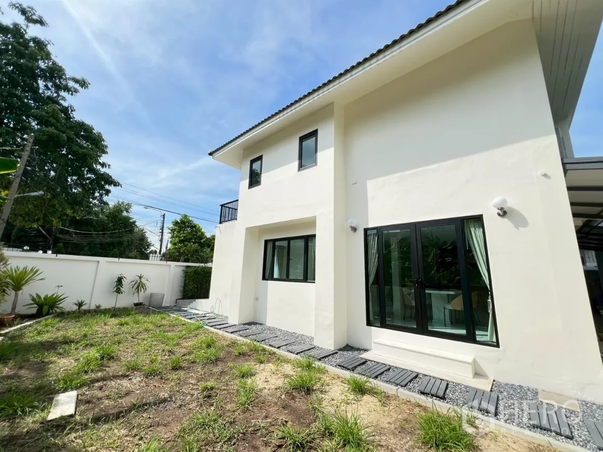 บ้าน ให้เช่าในSuan Luang, Bangkok - สนามหญ้าหลังบ้านและทางเดินข้างกำแพงสีขาวกับประตูกระจกเลื่อน.