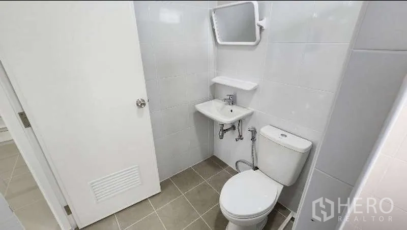 Factory for rent in Bang Bo, Samut Prakan - Compact bathroom with toilet, sink and mirror in neutral tiles