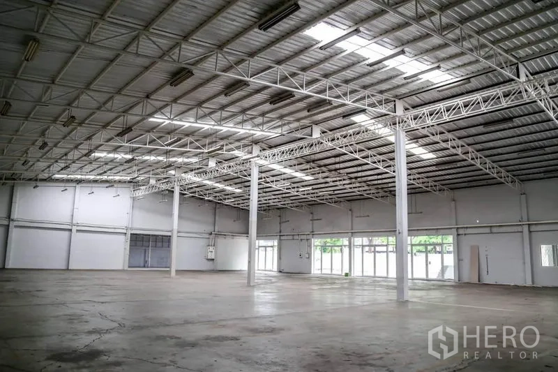 Warehouse for rent in Din Daeng, Bangkok - Open-plan warehouse hall from another angle showing translucent roof panels, structural columns and wide glass doors.