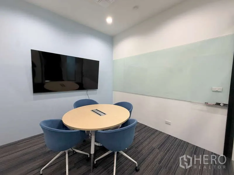 Office Space for rent in Huai Khwang, Bangkok - Compact meeting room featuring a round table, four blue chairs, wall-mounted screen and glass whiteboard.