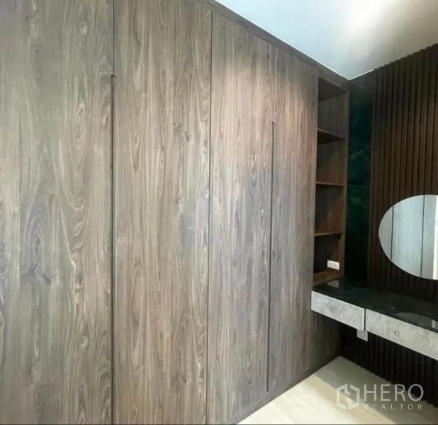 Condominium for rent or sale - Built-in wooden wardrobes and vanity with shelving and a round mirror.