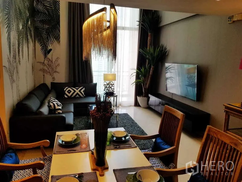 Condominium for sale in Sathon, Bangkok - Bright lounge with balcony access, large wall-mounted TV, indoor plants and tall curtains.