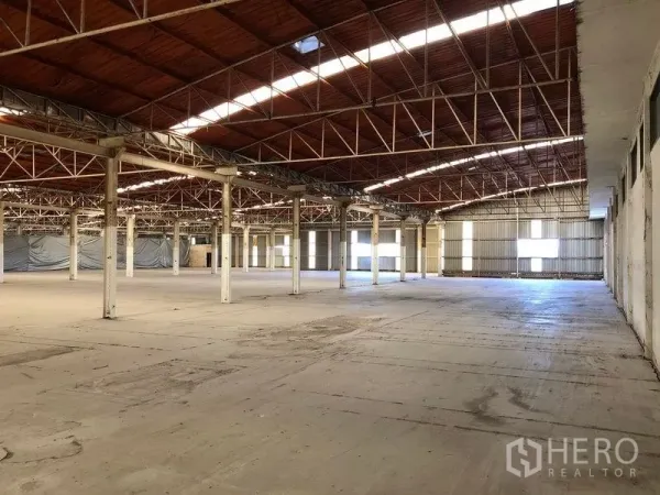 Factory for rent in Bang Phli, Samut Prakan - Expansive production hall with red steel truss roof, skylight strips and smooth concrete flooring across multiple bays.
