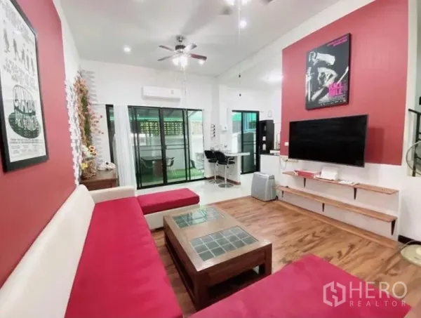 Townhouse for rent in Wang Thonglang, Bangkok - Bright living room with red accent walls, wall-mounted TV, and sliding glass doors to the patio.