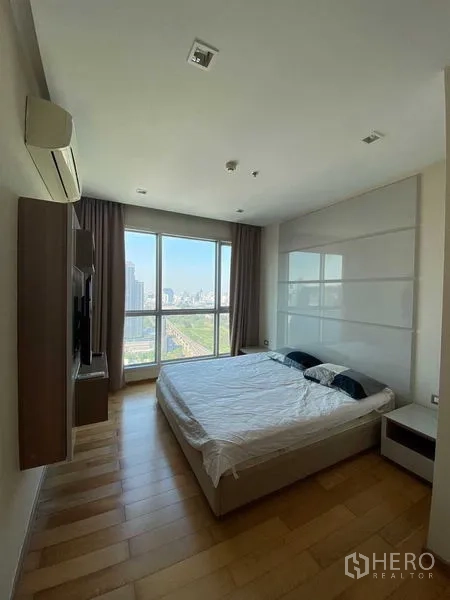 Condominium for sale in Ratchathewi, Bangkok - Master bedroom with king bed, wood floors and large window overlooking the city.