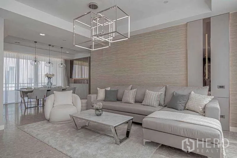 คอนโด ให้เช่าหรือขายในWatthana, Bangkok - ห้องนั่งเล่นโอเพ่นสเปซ โซฟาเข้ามุม โคมไฟทรงเรขาคณิต และพรมโทนอุ่น.